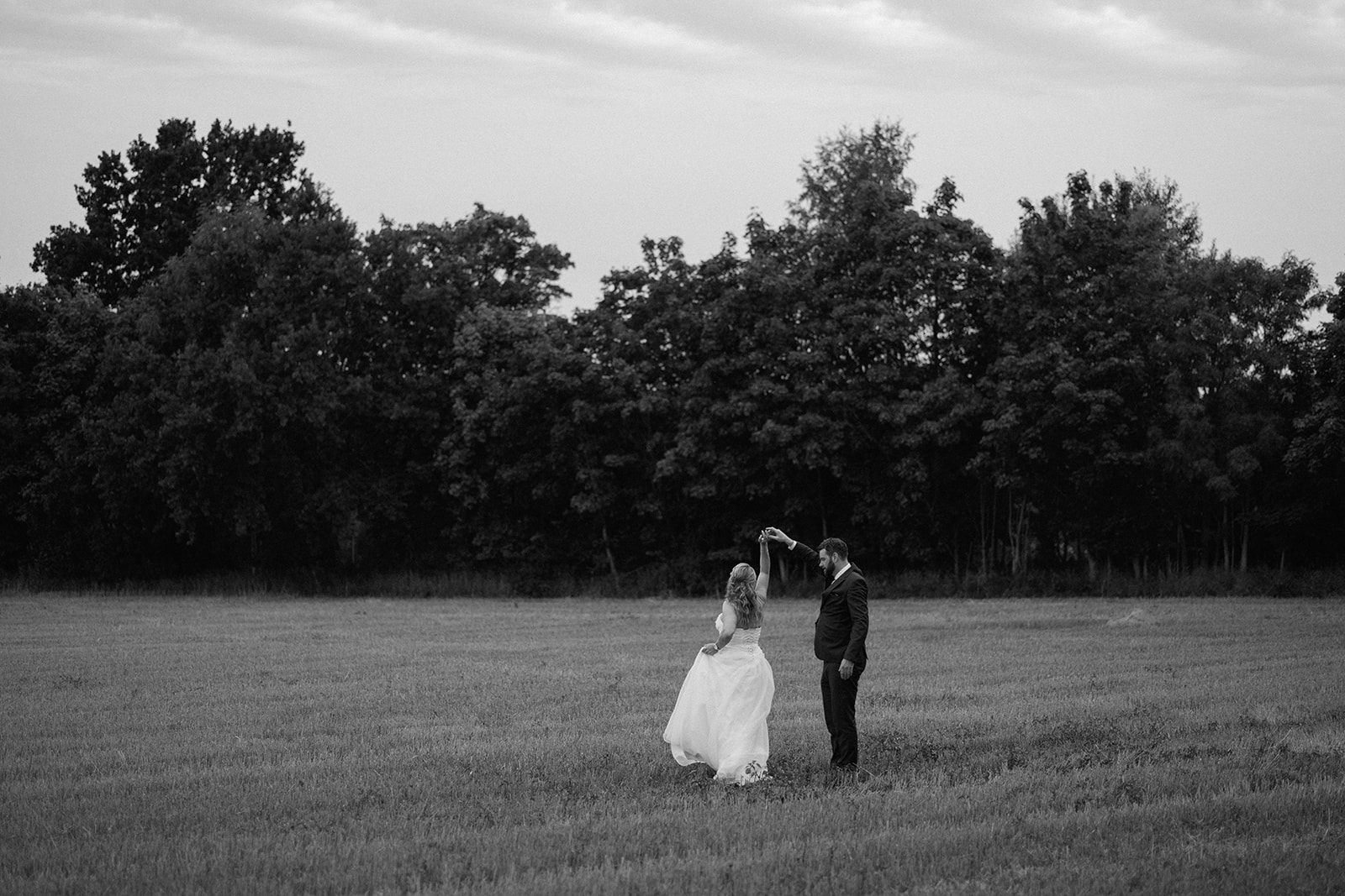 Bride and groom dancing in a field in black and white